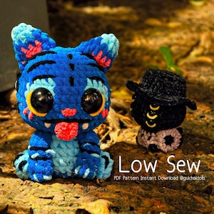 May include: A blue and black crocheted cat doll with large black eyes and a red tongue sticking out. Next to it is a small black doll wearing a black hat. The text "Low Sew" is visible.