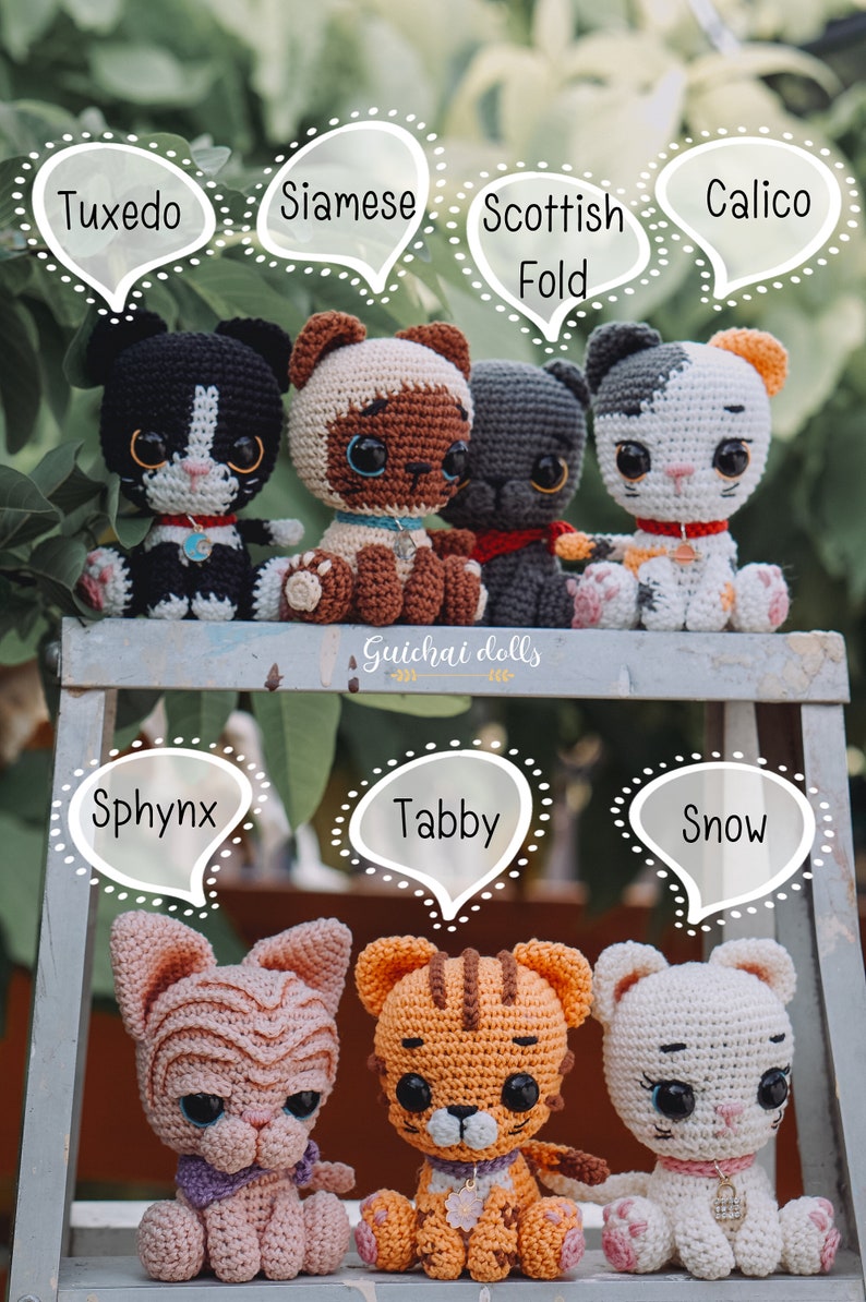 May include: A collection of crocheted cat dolls, each with a different breed name. The dolls are sitting on a wooden ladder, with the names of the breeds written in speech bubbles above them. The breeds include Tuxedo, Siamese, Scottish Fold, Calico, Sphynx, Tabby, and Snow.