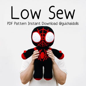 May include: A black and red crocheted doll with large white eyes and a spiderweb pattern on the head and chest. The text above reads Low Sew PDF Pattern Instant Download @guichaidolls. The doll has a rounded head and a sturdy, plush body.
