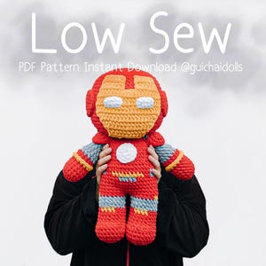 May include: A handmade, crocheted Iron Man doll in red, yellow, and blue. The doll features a helmet, chest emblem, and details mimicking the superhero's suit. The text "Low Sew" and pattern details are visible in the image.