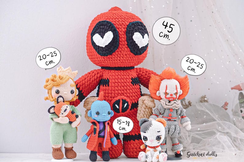 K&ouml;nnte beinhalten: F&uuml;nf geh&auml;kelte Pl&uuml;schtiere, darunter eine rote Deadpool-Figur, eine blaue Figur mit einem roten Umhang, eine gelbe Figur mit einer Krone, eine graue Figur mit einer roten Nase und eine wei&szlig;e Katzenfigur. Die Spielzeuge stehen alle auf einer wei&szlig;en Oberfl&auml;che mit einem wei&szlig;en T&uuml;llhintergrund. Die Spielzeuge sind alle unterschiedlich gro&szlig;, wobei die Deadpool-Figur mit 45 cm die gr&ouml;&szlig;te ist, die anderen Figuren 20-25 cm gro&szlig; sind und die blaue Figur 15-18 cm gro&szlig; ist.