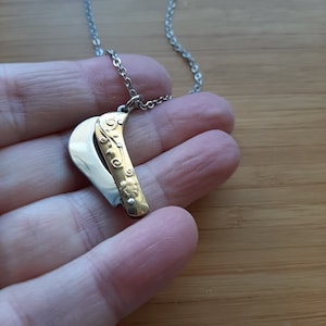 May include: A gold and silver necklace with a pendant shaped like a pocket knife. The knife is closed and has a floral design on the handle.
