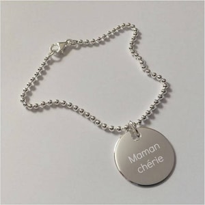 May include: A silver chain bracelet with a round charm that says "Maman chérie" in white lettering.