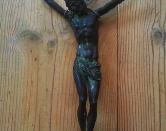 May include: A dark green metal sculpture of a person with outstretched arms, mounted on a wooden surface.