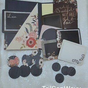 May include: A black folder with a floral design and a pocket on the front. The folder has a black frame with the word "Love" written in white. There are several black and white floral patterned circles and black circles with a scalloped edge.