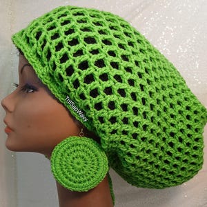 May include: A bright green crochet hat with a large, open weave. The hat is worn by a person with large, round, green crochet earrings.