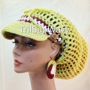 May include: A yellow crocheted hat with a visor, featuring a white and burgundy band. Matching earrings are also visible. The text "TrilSapWavy" is printed on the hat. The hat is a unique accessory.