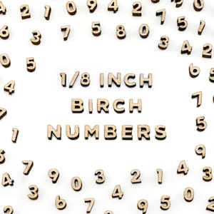 May include: A collection of small, wooden numbers scattered on a white surface. The numbers are in various sizes and orientations. Text in the center reads "1/8 INCH BIRCH NUMBERS". Ideal for crafts, scrapbooking, or educational projects.