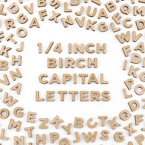 May include: A collection of wooden capital letters, scattered around a central display. The text "1/4 INCH BIRCH CAPITAL LETTERS" is prominently displayed. The letters are light brown and appear to be made of wood.
