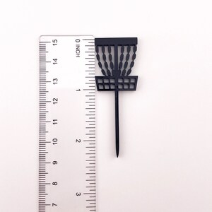 A single black acrylic disc golf basket cake topper against a ruler to show the height of a little over 2.25 inches tall.