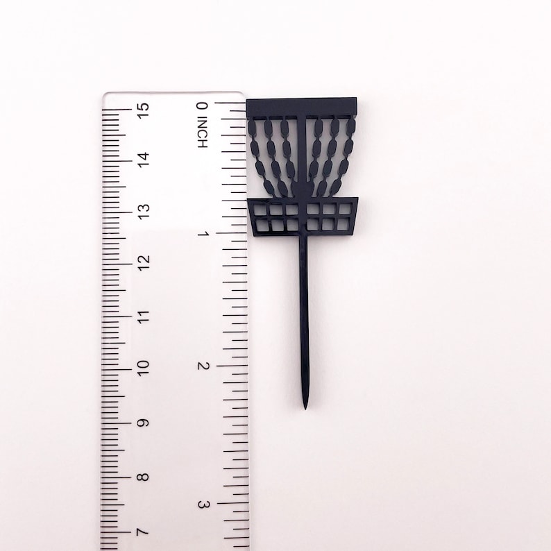 A single black acrylic disc golf basket cake topper against a ruler to show the height of a little over 2.25 inches tall.