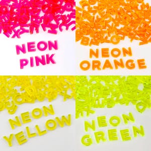 May include: Assortment of neon alphabet letter tiles in pink, orange, yellow, and green. The letters are arranged in a grid with the words "NEON PINK", "NEON ORANGE", "NEON YELLOW", and "NEON GREEN" spelled out below each color.