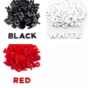 3 piles of half inch capital letters cut from acrylic. One pile of solid black letters, one pile of solid white letters, and one pile of solid red letters.