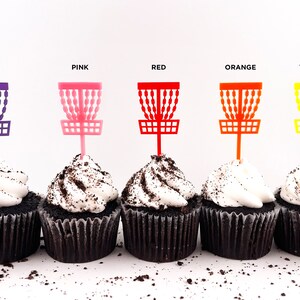 5 mini chocolate cupcakes with vanilla icing and cookie crumbles, decorated with tiny disc golf basket cupcake toppers in purple, pink, red, orange, and yellow.