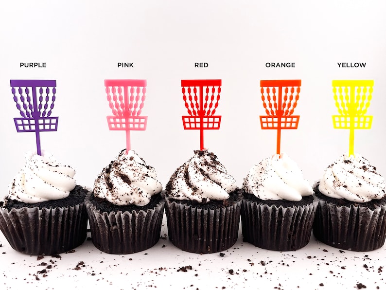 5 mini chocolate cupcakes with vanilla icing and cookie crumbles, decorated with tiny disc golf basket cupcake toppers in purple, pink, red, orange, and yellow.