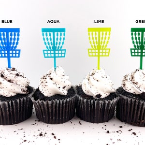 4 mini chocolate cupcakes with vanilla icing and cookie crumbles, decorated with tiny disc golf basket cupcake toppers in blue, aqua, lime, and green.