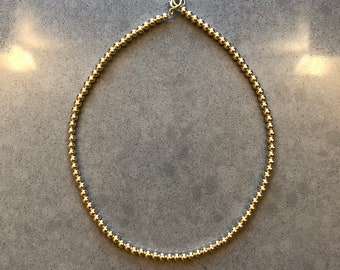 May include: A gold beaded necklace with a simple clasp.