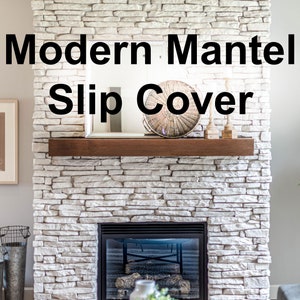 May include: A modern fireplace with a stone veneer. The fireplace features a dark wood mantel and a black fireplace insert. The text "Modern Mantel Slip Cover" is displayed above the mantel.
