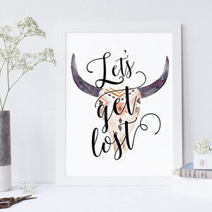 May include: A white printable art print with a black and white graphic of a bull skull with a geometric pattern on the skull. The text "Let's get lost" is written in black cursive font.
