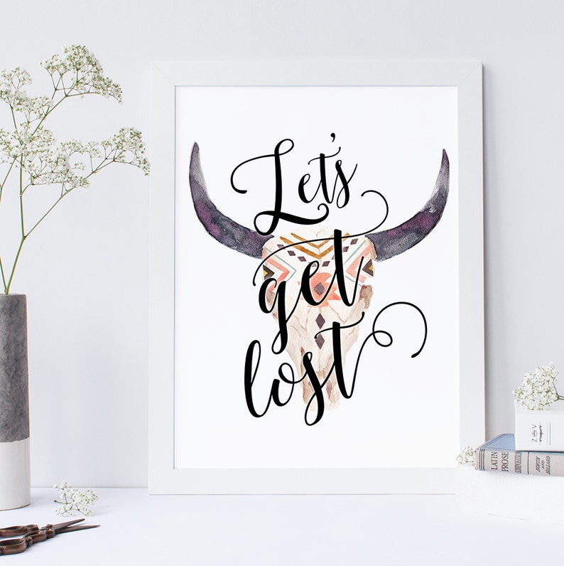 May include: A white printable art print with a black and white graphic of a bull skull with a geometric pattern on the skull. The text "Let's get lost" is written in black cursive font.
