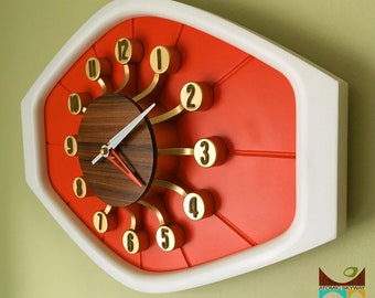 May include: A red and white clock with gold accents and a wood face. The clock has a unique design with the numbers extending out from the center.