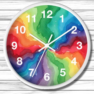 May include: A round wall clock with a white frame. The clock face features a vibrant watercolor design in a rainbow of colors. White hands and numerals mark the time.