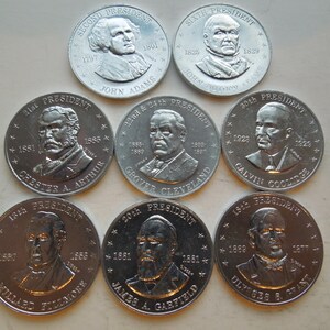 May include: A collection of silver-colored commemorative coins featuring portraits of U.S. Presidents. The coins display the names of the presidents, their terms, and the title "President". The coins are arranged in a circular pattern.