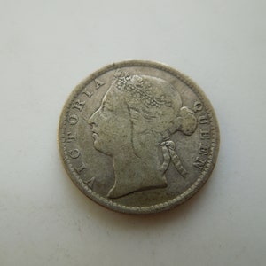 May include: A silver coin depicting Queen Victoria in profile, with the words "VICTORIA QUEEN" encircling the edge. The coin shows signs of wear, with intricate details visible, indicating its historical significance.