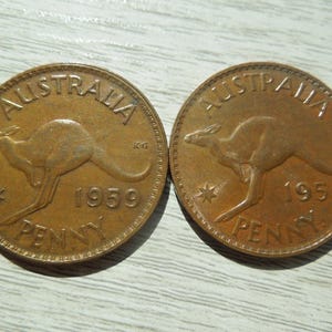 Puede incluir: Dos peniques australianos de color cobre de 1959. Cada moneda presenta un canguro, con la palabra "AUSTRALIA" arqueada en la parte superior y "PENNY" en la inferior. Tambi&eacute;n son visibles una estrella y el a&ntilde;o 1959.