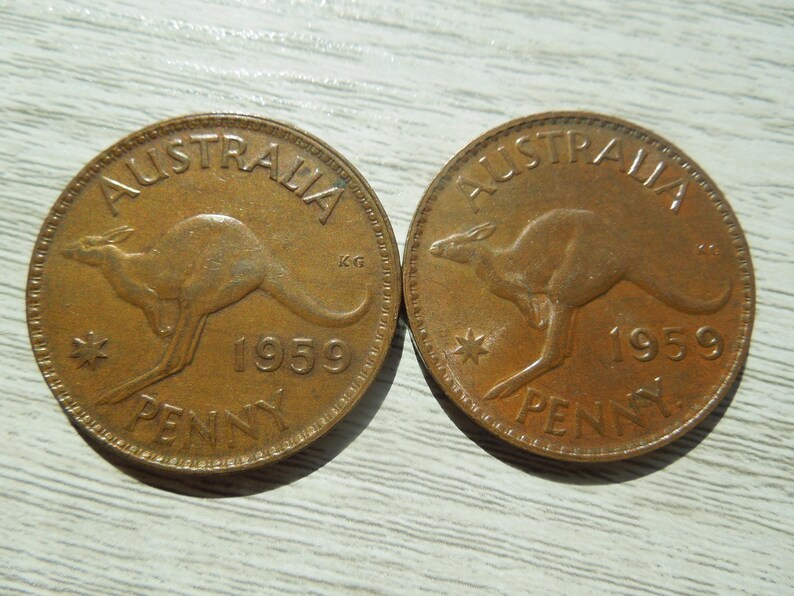 Puede incluir: Dos peniques australianos de color cobre de 1959. Cada moneda presenta un canguro, con la palabra "AUSTRALIA" arqueada en la parte superior y "PENNY" en la inferior. Tambi&eacute;n son visibles una estrella y el a&ntilde;o 1959.