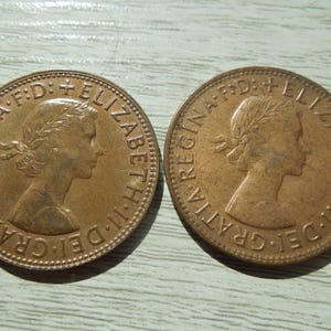 Puede incluir: Dos monedas de color bronce con el perfil de una mujer con una corona de laurel. Las monedas tienen la inscripci&oacute;n "ELIZABETH II DEI GRATIA REGINA F.D."