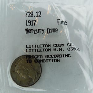 May include: A 1917 Mercury Dime coin in a plastic bag. The coin is graded "Fine" by Littleton Coin Co. in Littleton, New Hampshire.