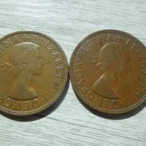 Puede incluir: Dos monedas de bronce antiguas con el perfil de una mujer y la inscripci&oacute;n "ELIZABETH II DEI GRATIA REGINA". Las monedas son circulares, con un borde texturizado y muestran signos de edad y desgaste.