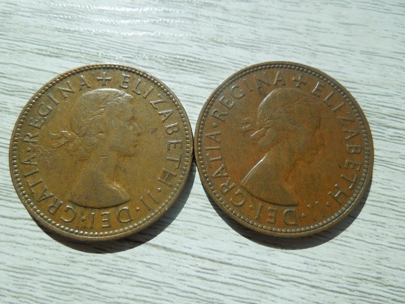 Puede incluir: Dos monedas de bronce antiguas con el perfil de una mujer y la inscripci&oacute;n "ELIZABETH II DEI GRATIA REGINA". Las monedas son circulares, con un borde texturizado y muestran signos de edad y desgaste.