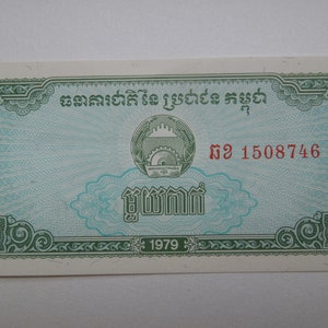 May include: A vintage Cambodian banknote with detailed green and blue patterns. The note displays Khmer script, a central emblem, and the year "1979". The serial number "2 1508746" is printed in red.