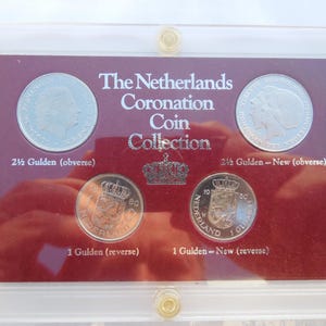 May include: A red velvet display case with four silver coins. The coins are from The Netherlands Coronation Coin Collection. The coins are 2 1/2 Gulden, 2 1/2 Gulden-New, 1 Gulden, and 1 Gulden-New.