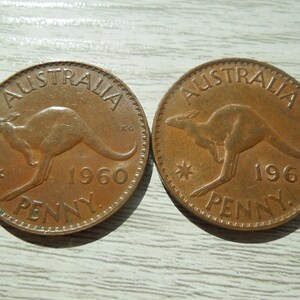 Puede incluir: Dos monedas de penique australianas de color cobre. Cada moneda presenta un canguro, la palabra "AUSTRALIA" en la parte superior y el a&ntilde;o de acu&ntilde;aci&oacute;n, 1960 o 1961, con la palabra "PENNY" en la parte inferior.