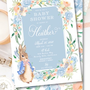 May include: A blue and white baby shower invitation with a floral border and a cartoon rabbit. The invitation says "Join us for a Baby Shower in honour of Heather" and includes the date, time, location, and registry information.