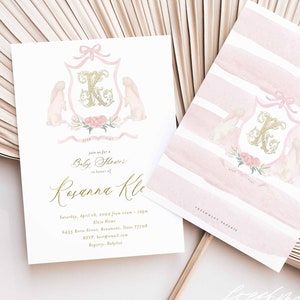 May include: Pink and gold baby shower invitation with a crest featuring a letter K, two bunnies, and floral accents. The text reads "Join us for a Baby Shower in honor of Ryann Kle..."
