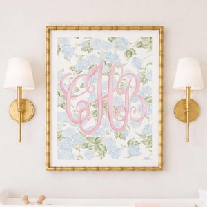 May include: A rectangular wall art print in a gold bamboo-style frame featuring a light blue hydrangea floral pattern with a large, ornate pink script monogram of the letters HB centred on the white background, displayed above a white crib.