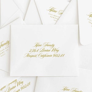 May include: A collection of white envelopes with gold-colored text. The text includes the name "Kline Family" and an address: 2564 Benton Way, Newport, California 90241. The envelopes are arranged in a slightly overlapping pattern.