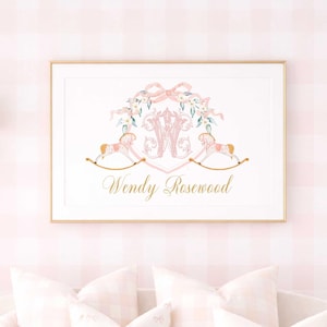 May include: A framed print with a gold border featuring a pink and gold design. The design includes a floral wreath, rocking horses, and the name "Wendy Rosewood" in gold script. The print hangs above a pink couch with pillows.