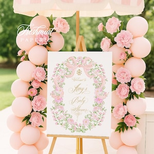 May include: A baby shower scene with a sign that reads "Welcome to Amy's Baby Shower." The sign is surrounded by a floral wreath and set on a wooden easel. Pink balloons and flowers decorate the scene, with a striped pink and white umbrella overhead.
