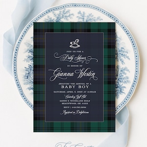 May include: A rectangular baby shower invitation card featuring a dark green and navy blue tartan border surrounding a central navy blue panel with white text that reads Join us for a Baby Shower in honour of Gianna Westin awaiting the arrival of a baby boy.