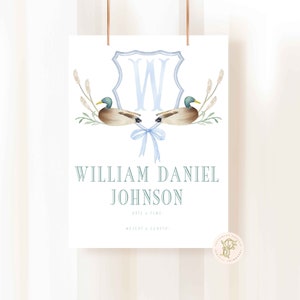 May include: A blue and white monogram with the letter W in a shield shape, flanked by two watercolor ducks. The text below reads "William Daniel Johnson" with the words "Date & Time" and "Weight & Length" in smaller font.