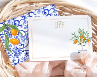 Może przedstawiać: Biała kartka z złotą ramką i monogramem "EFH" w złotych literach. Na kartce znajduje się akwarelowy rysunek małego drzewa pomarańczowego z pomarańczowymi owocami w niebiesko-białej doniczce. Kartka leży na niebiesko-białej kopercie.