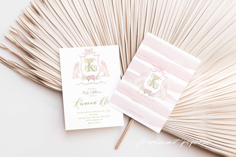 May include: Pink and gold baby shower invitation with a crest featuring a letter K, two bunnies, and floral accents. The text reads "Join us for a Baby Shower in honor of Ryann Kle..."