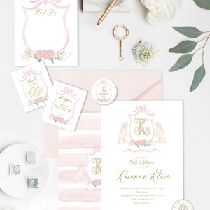 May include: Pink and gold baby shower invitation with a watercolor design featuring a shield with a pink bow, a gold letter K, and two white bunnies. The text reads "Join us for a Baby Shower in honor of Rosanna Klein".