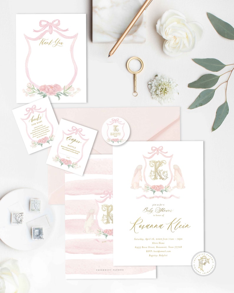 May include: Pink and gold baby shower invitation with a watercolor design featuring a shield with a pink bow, a gold letter K, and two white bunnies. The text reads "Join us for a Baby Shower in honor of Rosanna Klein".