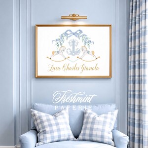 Peut inclure: Une affiche encadr&eacute;e avec un cadre dor&eacute;, orn&eacute;e d'un n&oelig;ud bleu, d'&eacute;l&eacute;ments floraux et de deux chevaux &agrave; bascule. L'affiche comprend le nom "Luca Charles Gianola" en lettres dor&eacute;es. L'image est affich&eacute;e au-dessus d'un fauteuil bleu avec des coussins &agrave; carreaux.